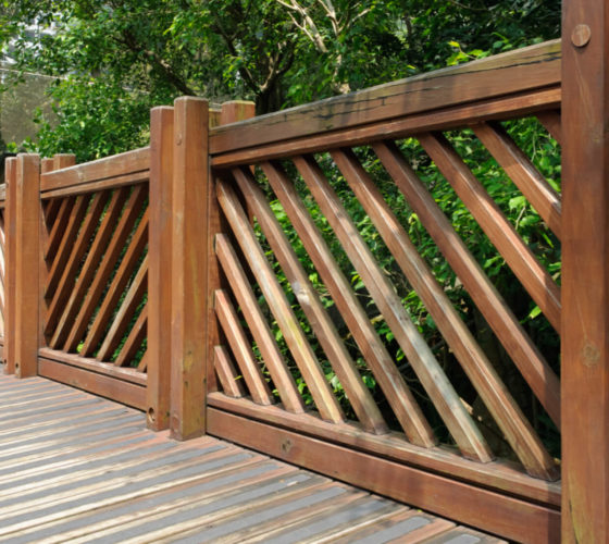 A sturdy, wooden fence runs alongside a pathway made of wooden beams.