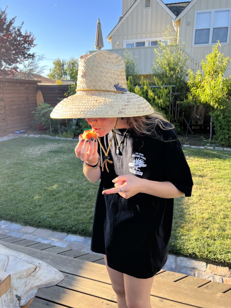 A photo of a person eating a peach in a backyard.