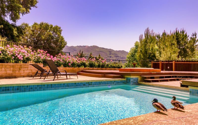A photo of a property in California with a pool surrounded by a patio and gardens.