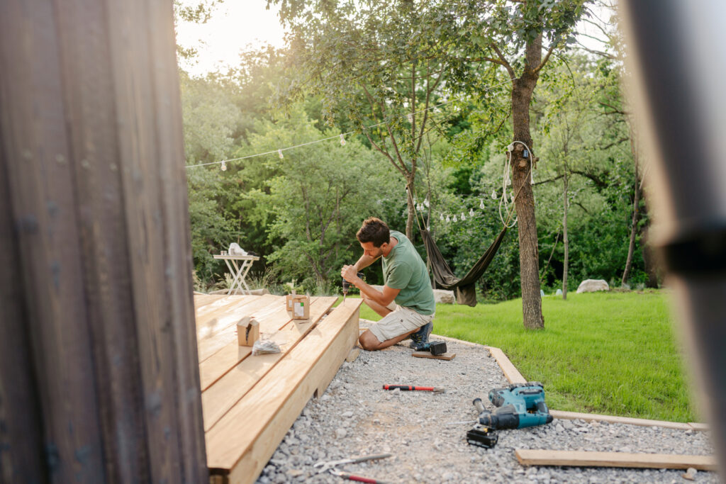 Photo of a carpenter attaching decking boards to a deck of a house.