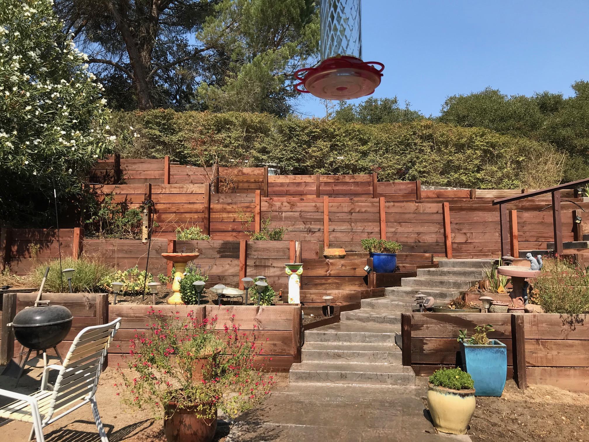 Tiered timber retaining wall construction with garden beds and concrete steps